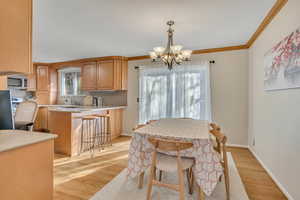 Dining room featuring light wood-style floors, a chandelier, and crown molding