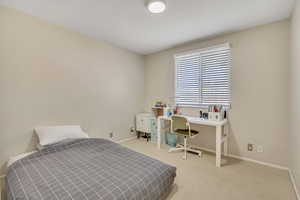 Bedroom with light colored carpet and a desk