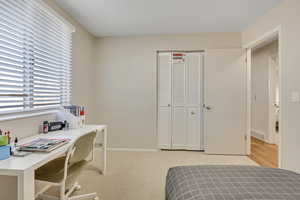 Bedroom with light colored carpet, a closet, and a desk