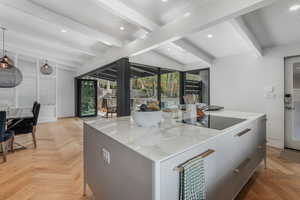 Kitchen with modern cabinets, a kitchen island, recessed lighting, black electric cooktop, and light stone countertops