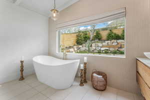 Bathroom with vanity, a soaking tub, vaulted ceiling, brick wall, and light tile patterned floors