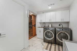 Laundry room featuring light marble finish floors, independent washer and dryer, recessed lighting, and cabinet space