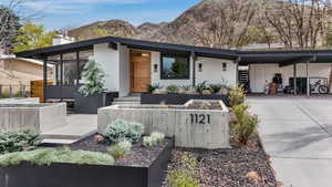 View of front of house with a carport, driveway, a chimney, stucco siding, and a mountain view
