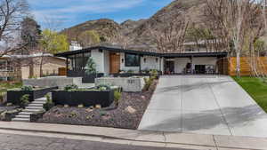 View of front of home featuring stucco siding, driveway, a mountain view, and a chimney