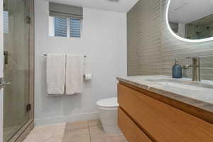 Full bathroom featuring a stall shower, vanity, light tile patterned floors, and decorative backsplash