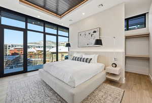 Bedroom featuring expansive windows, light wood-style flooring, a mountain view, recessed lighting, and access to outside