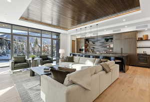 Living area featuring a raised ceiling, expansive windows, wooden ceiling, recessed lighting, and light wood finished floors