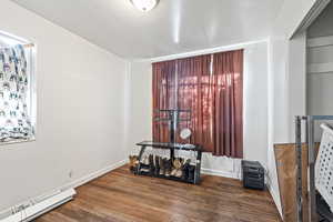 Unfurnished room featuring dark wood-type flooring and a baseboard heating unit