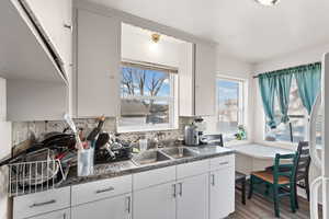 Kitchen featuring white cabinets, light wood finished floors, and freestanding refrigerator