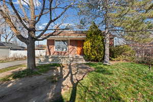 View of front of house with a front yard, brick siding, and covered porch