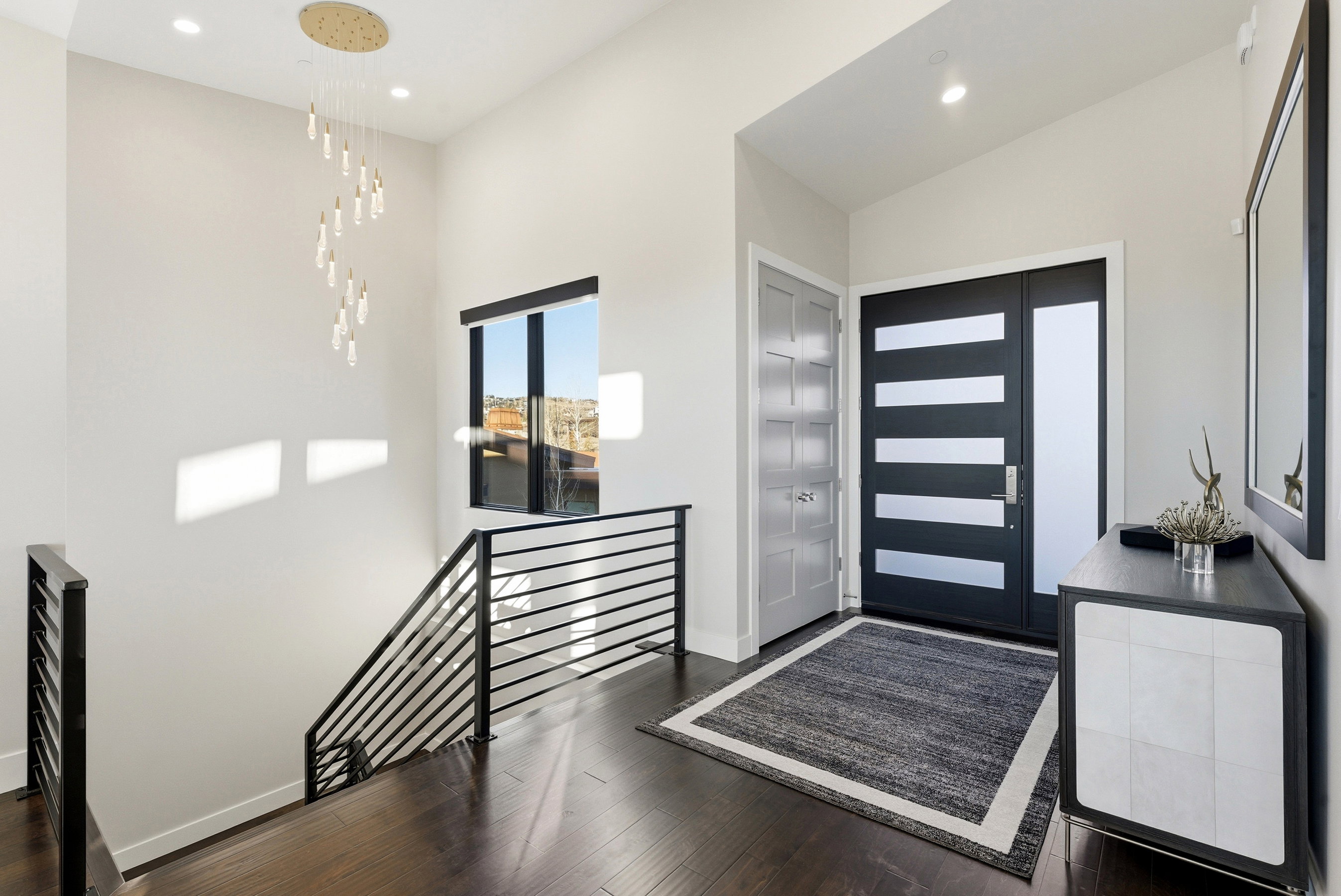 Entryway featuring a contemporary door with frosted glass panels, wood-finish flooring, and a modern chandelier