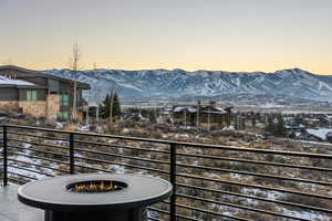 Snow covered back of property with a mountain view and an outdoor fire pit