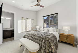 Bedroom with light carpet, a ceiling fan, and ensuite bath
