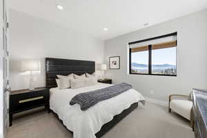 Bedroom with light colored carpet, recessed lighting, and a mountain view