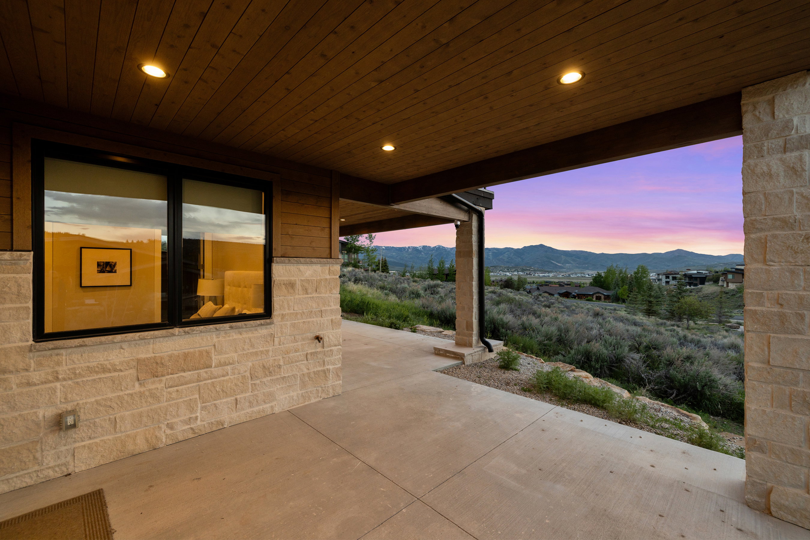 Covered patio featuring a concrete surface, stone veneer wall, recessed lighting, and wood-paneled ceiling
