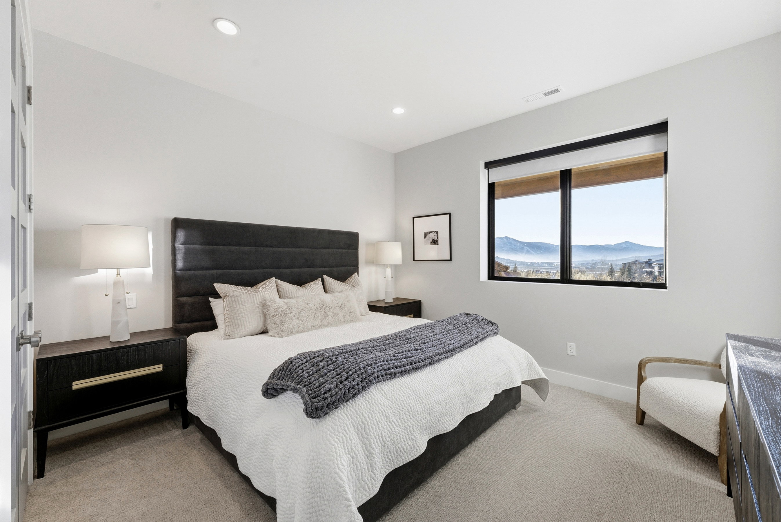 Recessed lighting illuminates a carpeted bedroom with a large window