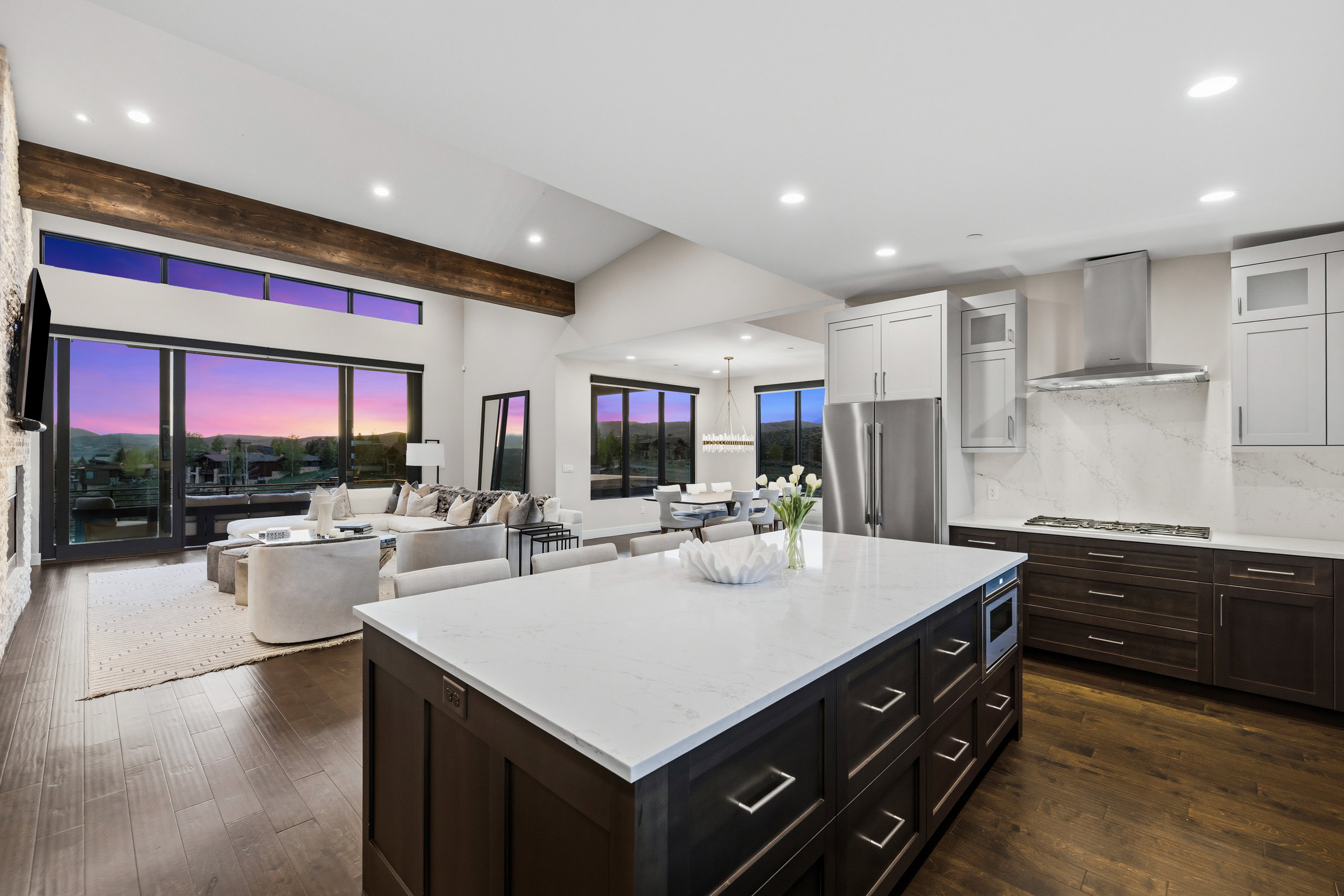 Expansive open-concept living space featuring a gourmet kitchen, a large central island with integrated microwave, and a gas range with stainless steel hood