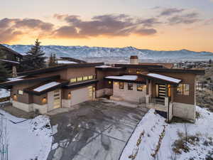 View of front of property featuring a chimney, stone siding, a mountain view, and driveway