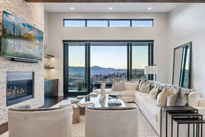 Living room with a high ceiling, a mountain view, wood finished floors, beamed ceiling, and a stone fireplace