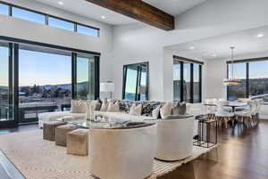Living area featuring plenty of natural light, dark wood-style floors, beam ceiling, a chandelier, and recessed lighting