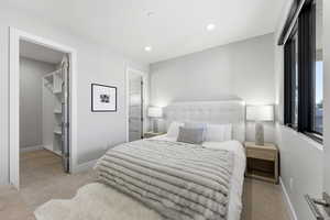 Bedroom featuring light carpet, a spacious closet, and recessed lighting