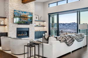 Living room featuring hardwood / wood-style floors, a towering ceiling, a fireplace, and beamed ceiling