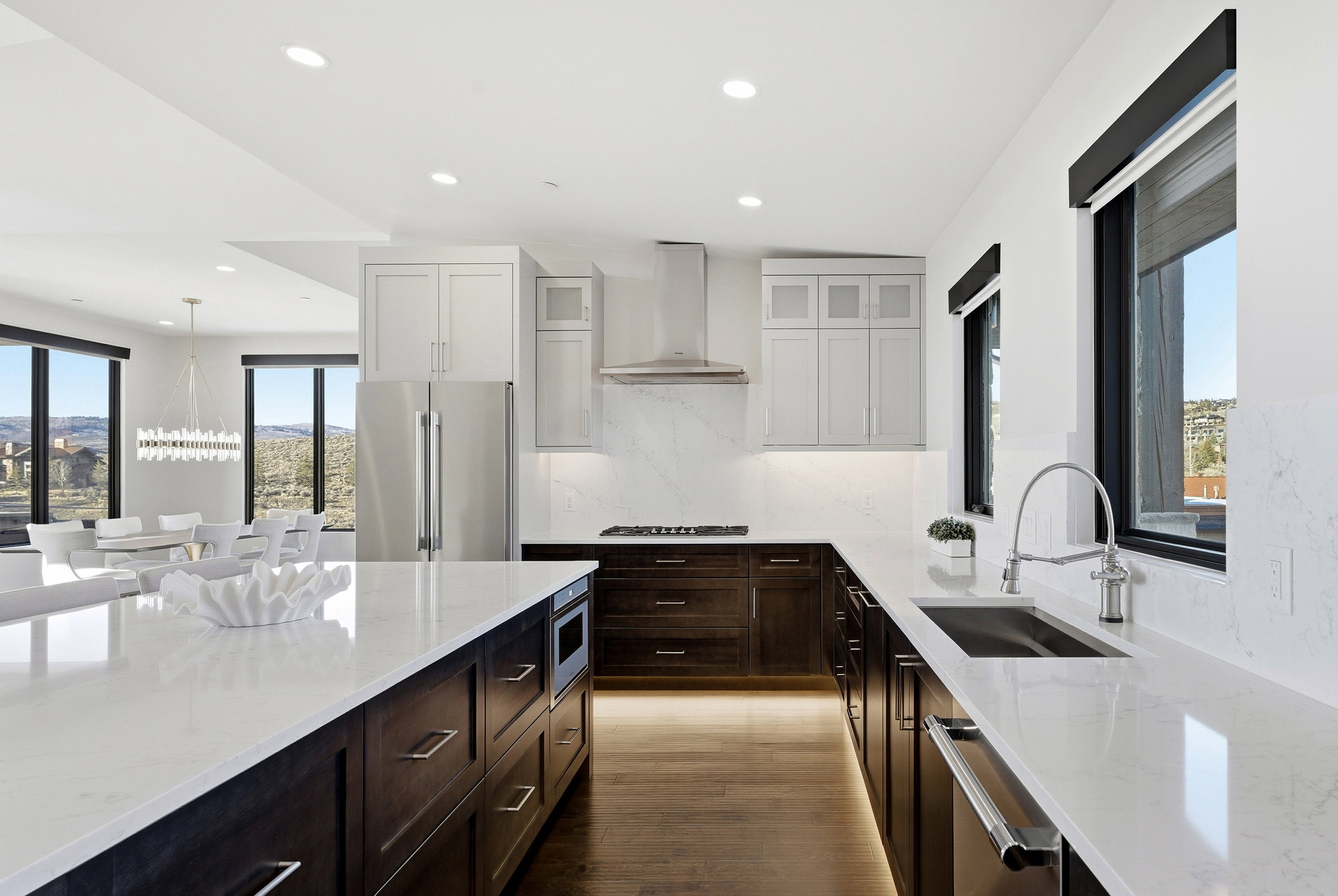 Gourmet kitchen with expansive white countertops, dark wood cabinetry, and integrated stainless steel appliances