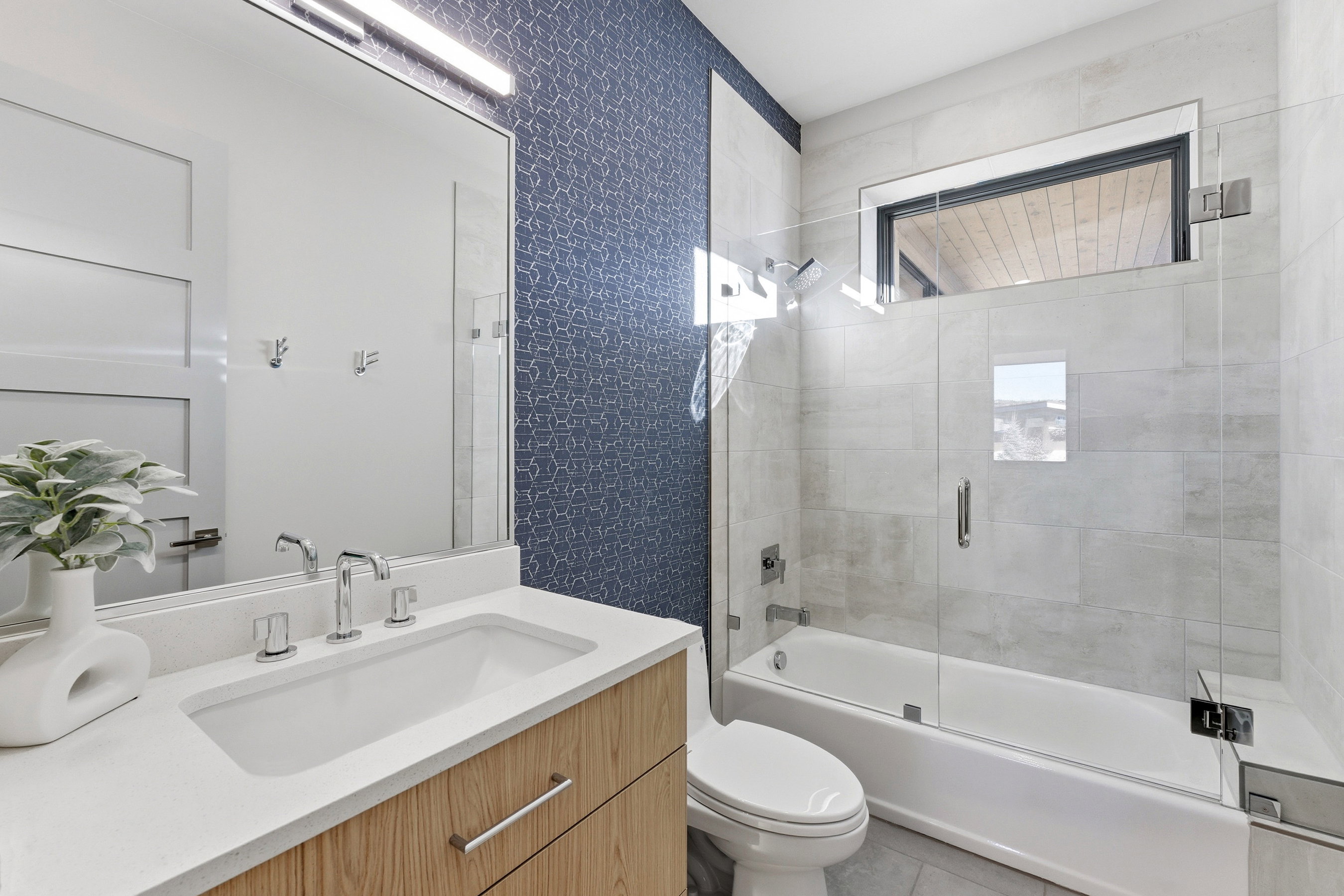 Contemporary bathroom featuring a wood-finish vanity with an integrated sink and chrome fixtures