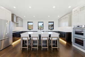 Kitchen featuring glass insert cabinets, appliances with stainless steel finishes, a breakfast bar area, a kitchen island, and recessed lighting