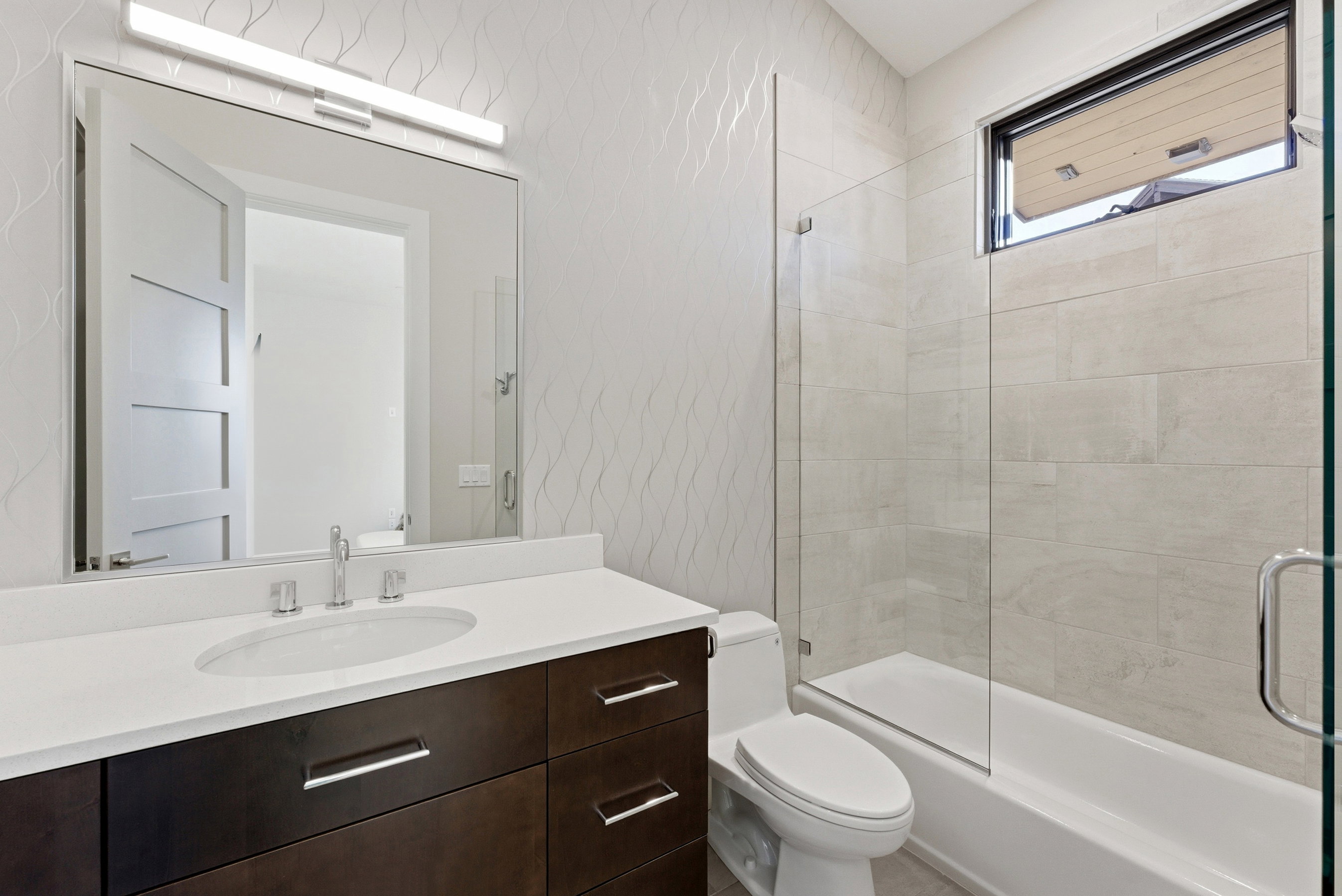 Modern bathroom featuring a dark wood-finish vanity with a white countertop and rectangular undermount sink