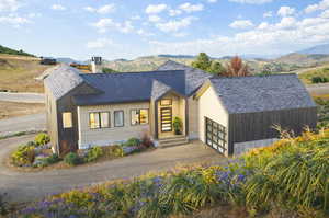 View of front of home with a mountain view, driveway, a chimney, and a garage