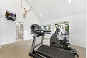 Exercise room with high vaulted ceiling, light carpet, and recessed lighting