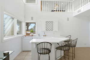 Kitchen featuring light countertops, a breakfast bar, a high ceiling, and white cabinets