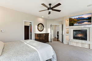 Bedroom with a ceiling fan, a glass covered fireplace, carpet flooring, and recessed lighting