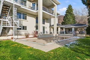Rear view of house with stucco siding, a yard, a balcony, swimming pool and a patio