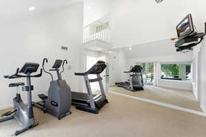 Workout area with high vaulted ceiling and recessed lighting