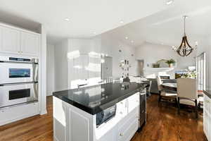 Kitchen with white cabinetry, stainless steel double oven, open floor plan, a center island, and dark wood-style flooring