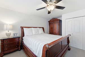 Bedroom featuring light carpet, a ceiling fan, and a closet
