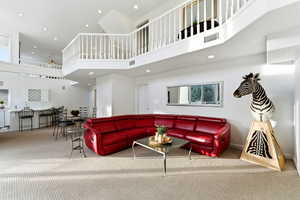 Carpeted living area featuring a high ceiling and recessed lighting