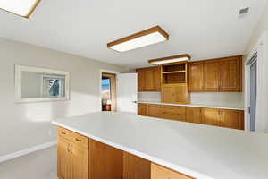 Craft room with brown cabinets, light countertops, and light carpet