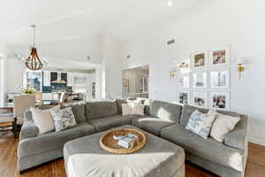 Living area featuring wood finished floors, high vaulted ceiling, recessed lighting, and a chandelier