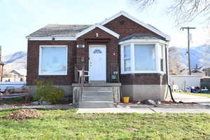 View of front of home featuring brick siding, a front yard, and a mountain view