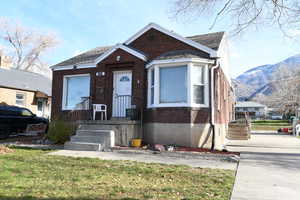 Bungalow-style house with brick siding, a mountain view, and a front lawn