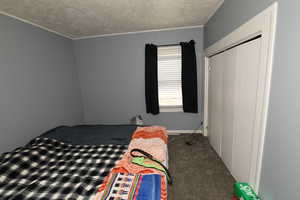 Bedroom with a closet, a textured ceiling, and carpet floors