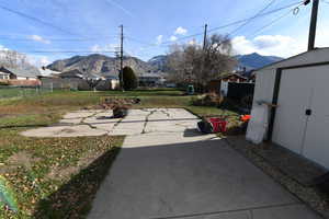 Fenced backyard featuring a patio, a mountain view, and a storage unit