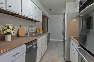 Kitchen featuring white cabinets, appliances with stainless steel finishes, light wood-style floors, and light countertops
