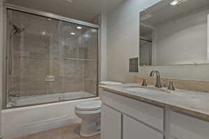 Bathroom featuring vanity, shower / bath combination with glass door, and light tile patterned flooring