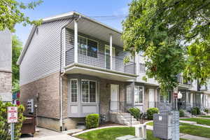 View of front of property with a balcony and brick siding