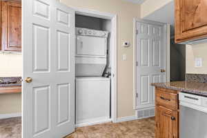 Laundry area featuring stacked washer and clothes dryer and baseboards