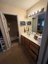 Primary Bathroom with vanity, connected bathroom, a textured ceiling, bathing tub / shower combination, and dark carpet
